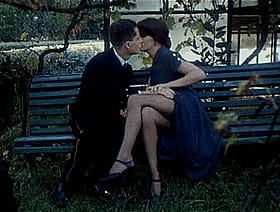 Cuddling on the Bench: A Couple's Outdoor Kissing Session'